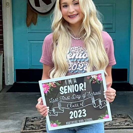 A Girl Holds a Sign for Her First Day of Senior Year in High School
